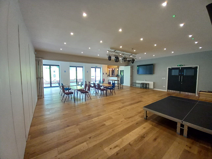 View across the new community multi-function room towards the Milkchurn Caf&eacute; counter and French windows opening onto the terrace.