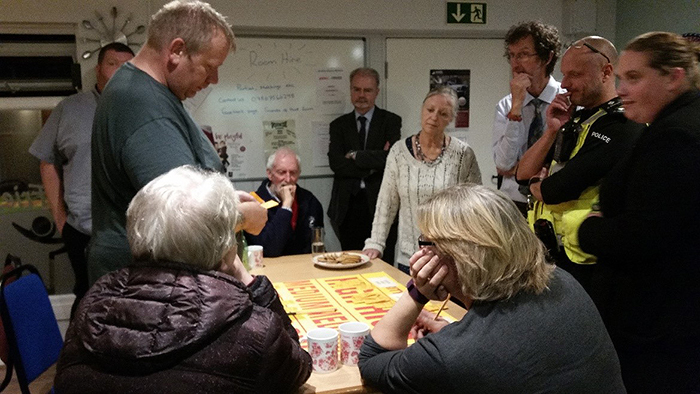 Community planning event showing residents and partners gathered around a table assessing and planning consultation outcomes